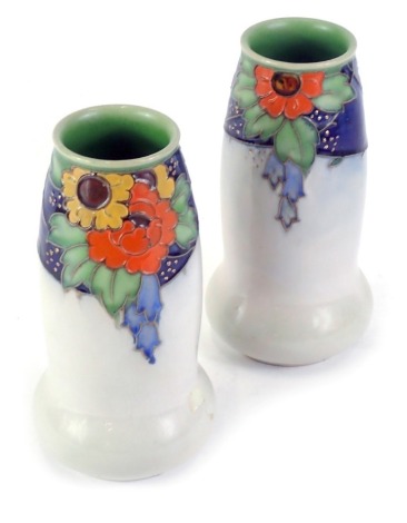 A pair of Royal Doulton stoneware vases, with tube lined decoration of orange, blue, green and yellow flowers, on a cobalt blue ground picked out in gilt, above a broad grey band, incised artists marks for possibly Christina Abbott, 20cm high.