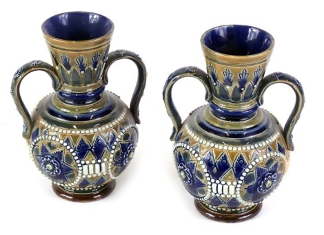 A pair of Doulton Lambeth stoneware two handled vases, decorated with roundels within beaded leafy border in the manner of Tinworth, indistinct differing decorated initials to underside, 13cm high. (AF)