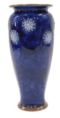 A Royal Doulton stoneware vase, on a Royal blue ground with raised relief of flowers, stamped to underside, 26cm high.