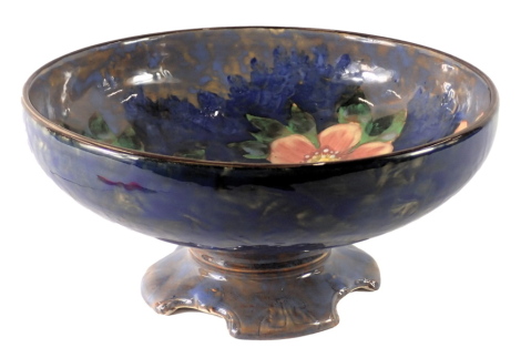 A Royal Doulton Pansies pattern centre bowl, of plain design with pink and red pansies, on a four stepped foot, with green stamp to underside, 12cm high.