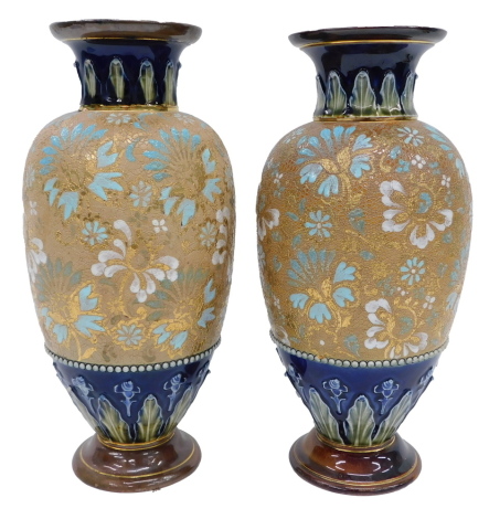 Two similar Doulton Lambeth ware vases, each with a blue and green tulip glazed rim, on a turquoise and white finished gilt brown mottled body, stamped to underside, 31cm and 30cm high. (2)