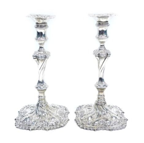 A pair of George III candlesticks, with shaped square detachable drip pans on waited cylindrical sconces and inverted baluster wrythens fluted stems and swept rounded square bases, cast with anthemion within a gadrooned border, London 1758, maker mark I.I