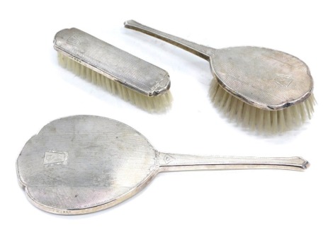 A George VI silver back three piece dressing table set, with engine engraved decoration, Birmingham 1943.