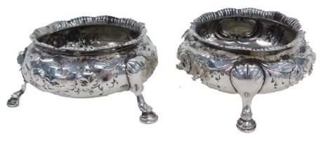 A pair of Victorian silver salts, with a fluted top and embossed floral body with vacant cartouche, on tripod legs, London, 4.29oz. (2)