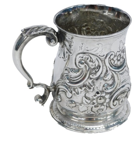 A George III silver tankard, embossed with scrolls around a vacant cartouche, on a tapering foot, with scroll handle, decoration possibly later, London 1781, 6.7oz, 9.5cm high.