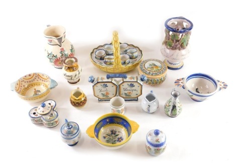 A quantity of French Faience ceramics, to include a puzzle jug, Quimper jar and cover, a vinaigrette, a trefoil shaped inkwell, egg cup stand, two handled bowls, etc.