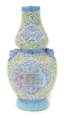 A 19thC Chinese porcelain double gourd vase, with lion dog and ring handles, decorated in relief with reserves of dragons, bats, and flowers, within a ground moulded with geometric lattice work, bears gilt six character Qianlong seal mark to base, 28cm hi