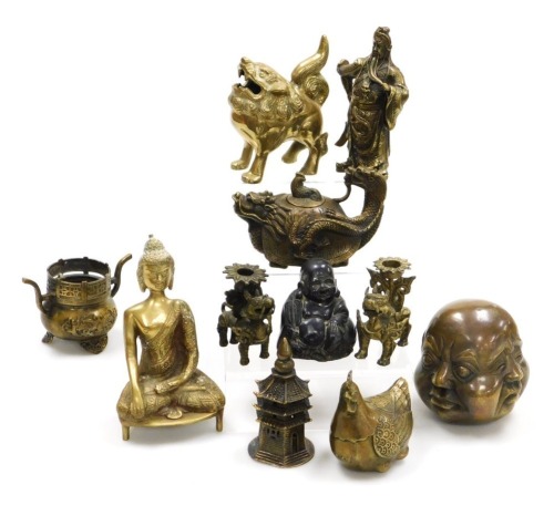 A group of Chinese brassware, including a pair of lion dog candlesticks, a dragon teapot, a four faces of Buddha bust paperweight, and figures of deities, together with a Tibetan figure of a seated Buddha, etc. (a quantity)