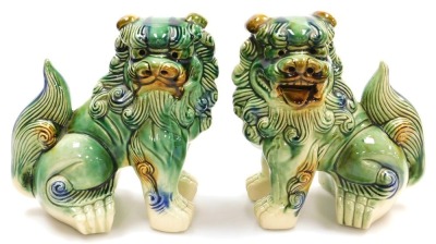 A pair of Chinese green glazed dogs of fo, modelled facing left and right in seated pose, 21cm wide.