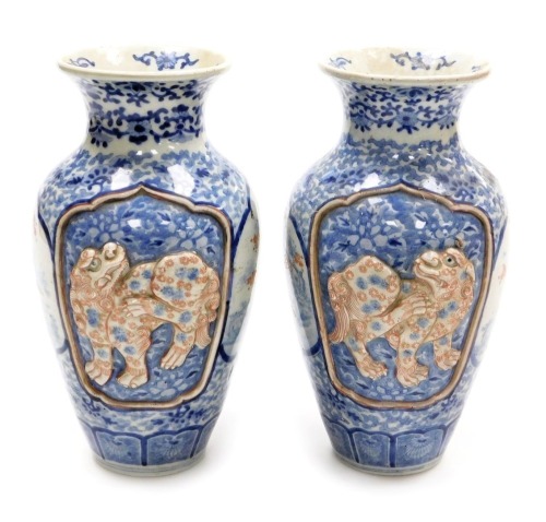 A pair of Meiji period Japanese blue and white vases, of shouldered, tapering form, decorated with reserve panels of relief decorated with shishi, interspersed with panels of birds and trees, on a blue and white floral and foliate ground, three character