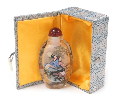 A 20thC Chinese inside painted glass snuff bottle, decorated with ladies in a garden, boxed, 11.5cm high.