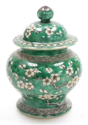 A Quing dynasty porcelain vase and cover, of baluster form, decorated with prunus blossom on a green ground, bears four character Kang-Hsi mark, 15cm high. (AF) - 2