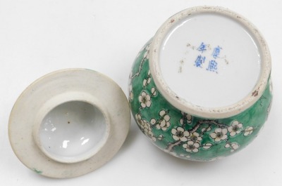 A Quing dynasty porcelain vase and cover, of baluster form, decorated with prunus blossom on a green ground, bears four character Kang-Hsi mark, 15cm high. (AF) - 6