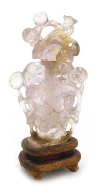 A Chinese quartz snuff bottle and stopper, carved with birds and berries, raised on a wooden stand, 8.5cm high.