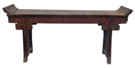 A Chinese hardwood altar table, the scroll ended top above a carved frieze, raised on trestle supports, with inset fretwork panels, 104cm high, 222cm wide, 45cm deep.