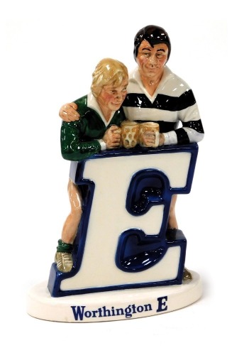 A Beswick Worthington E pottery advertising figure group, featuring two rugby players resting against the letter E, printed mark, 22cm high.