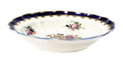 A Worcester first period porcelain soup plate, of circular fluted form, painted with sprays and sprigs of flowers within a cobalt blue border, gilt heightened, open blue crescent mark, 22.5cm wide.