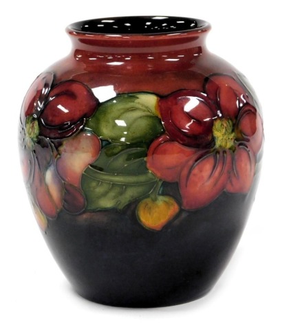 A Moorcroft Flambe pottery Clematis pattern vase, decorated on a red to blue ground, painted mark and paper label, Potter to the late Queen Mary, 14.5cm high.