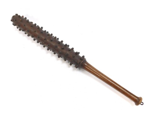 A World War One wooden trench club, the tapering handle joining a cylindrical club with various raised roundels, 80cm long.