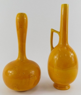 A Burmantofts faience bottle shaped vase, in okra decorated with incised sun motifs, impressed 1648, stamped to underside, 24cm high, together with a Burmantofts bottle shaped vase with handle, in okra, numbered 402, impressed to underside, 27cm high. (bo - 2