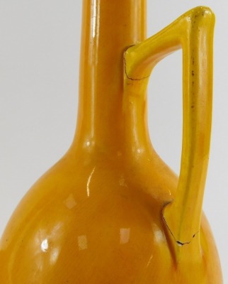 A Burmantofts faience bottle shaped vase, in okra decorated with incised sun motifs, impressed 1648, stamped to underside, 24cm high, together with a Burmantofts bottle shaped vase with handle, in okra, numbered 402, impressed to underside, 27cm high. (bo - 3