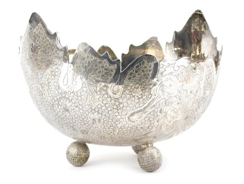 A Burmese white metal bowl, with shaped edge, the bowl decorated with leaves, flowers, etc., on three orb scaled feet, 19.2oz, 19cm diameter.