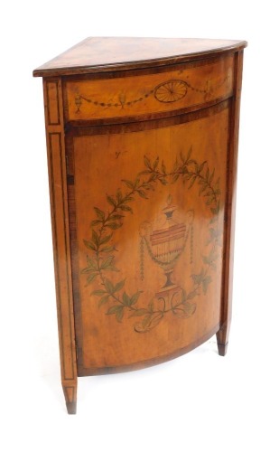 An Edwardian Neo Classical revival Edwards and Roberts mahogany and inlaid bow fronted corner cupboard, decorated to the door with an urn surrounded by leaves and fruit, on spade feet.