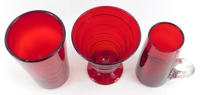 A Whitefriars studio glass ruby red vase, designed by Barnaby Powell, of conical design with raised trailing decoration, on out swept circular foot, pattern number 9296, 14cm high, a Whitefriars ruby glass wave ribbed glass, numbered 8473, 15cm high, and - 2