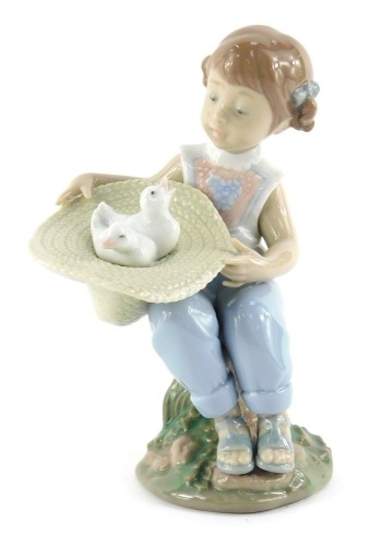 A Lladro porcelain figure, modelled as a seated girl holding upturned hat containing birds, printed marks, 16cm high.