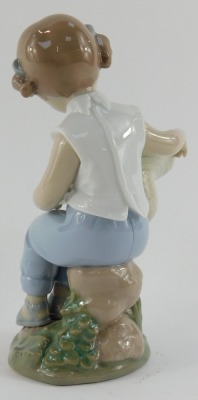 A Lladro porcelain figure, modelled as a seated girl holding upturned hat containing birds, printed marks, 16cm high. - 2