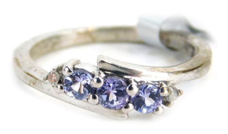 A silver dress ring, of two twist design set with three tanzanite stones with tiny diamond set ends, ring size J½, 2.2g all in.