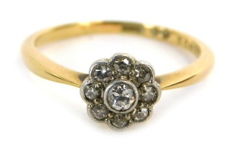 An 18ct gold diamond dress ring, the central floral cluster set with tiny diamonds, in rub over platinum setting, on a yellow metal band stamped 18, size N, 2.7g all in.