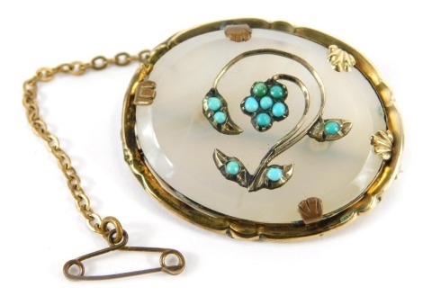 An Edwardian pendant, of oval design with a petallated and shell capped outer border, pinchbeck outer frame, with central turquoise flower designs, on moonstone effect ground, 3.5cm wide, on silver pin back with safety chain.