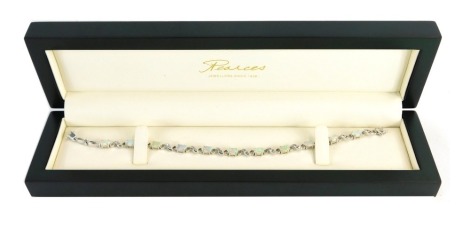 An 18ct white gold opal and diamond bracelet, the oval opals in claw setting with heart and twist design links, each set with three tiny diamonds, 20cm long, 14.4g all in, in Pearces box.