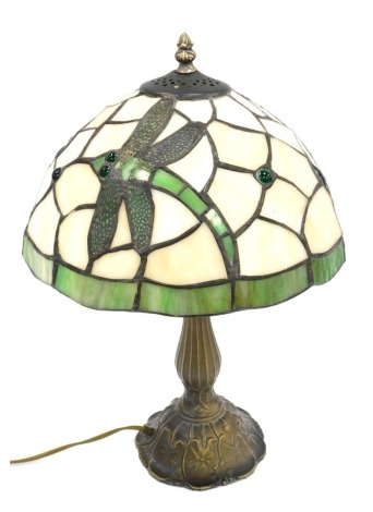 A Tiffany style table lamp, the leaded glass shade decorated with dragonflies against an off white and green ground, on a brass effect column base, 48cm high.