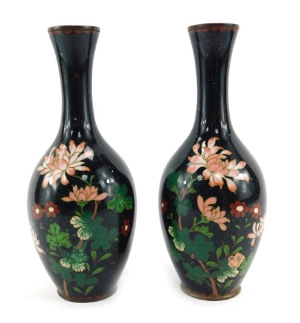 A pair of Japanese cloisonne vases, of cylindrical form with elongated neck, decorated with other flowers, against a dark green ground, 22cm high.