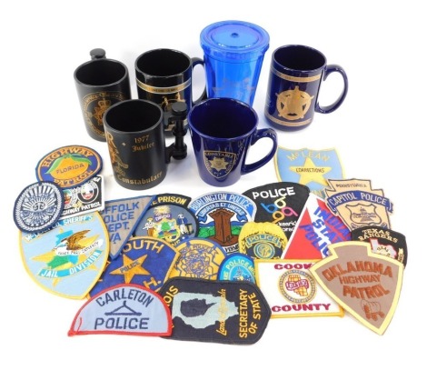 A group of Police related collectables, to include American Police cloth badges, West Burlington Iowa, Illinois, Oklahoma, Indiana, various mugs, etc. (1 tray)