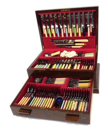 A mid century part canteen of cutlery, for twelve place settings, each piece with differing coloured moulded plastic handle, some pieces missing, contained in an oak case, 51cm wide.