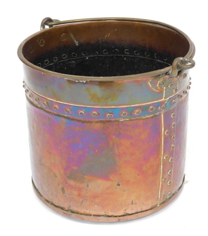 A copper coal bucket, of cylindrical form, with ring handle, decorated with a band of raised roundels, 30cm high, 34cm diameter.