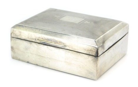 A George VI silver cigarette box, of rectangular form, the hinged lid with engine turned decoration, enclosing a treen lined interior, London 1939, 11cm wide. (AF)