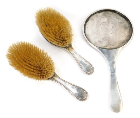 A George V silver backed dressing table set, comprising hand mirror, and two hairbrushes, each bright cut decorated with urn containing flowers, swags, etc, Birmingham 1912.