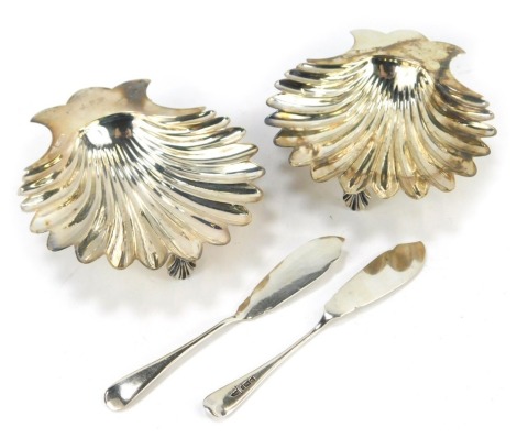 A pair of Edward VII butter dishes, of shell form, each raised on three shell cast feet, initialled engraved K P & J F P, by Walker and Hall Sheffield 1902, together with two silver butter knives, Sheffield 1901 and 1911, 6.23oz. (4)