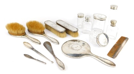 A George VI silver mounted harlequin dressing table set, comprising hand mirror, two hair brushes, two clothes brushes, comb, six cut glass dressing table bottles with silver tops, shoe horn, button hook, and file, each decorated with a cartouche initiall