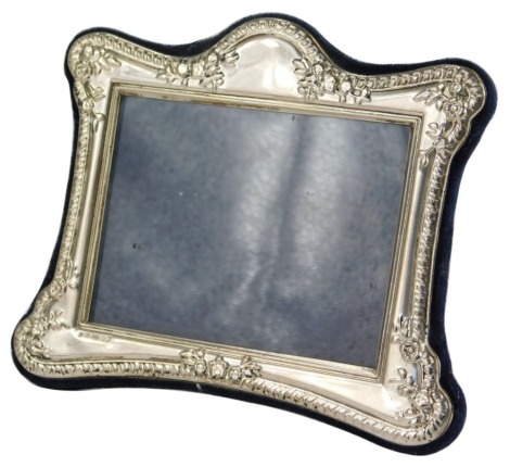 An Elizabeth II silver photograph frame, of shaped rectangular form, embossed with gadrooned border, flowers, leaves, etc., with velvet backing and strut support, London 1999, 15cm wide.