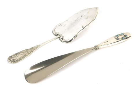 A Continental white metal cake slice, the handle decorated with flowers, scrolls, etc., marked 800, 2.08oz, together with a George VI silver an enamel handled shoe horn. (2)