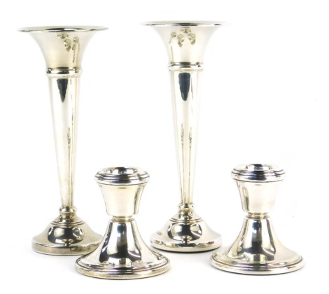 A pair of Elizabeth II bud vases, of trumpet form, on circular foot, loaded, Birmingham 1984 and 1982, 15cm high, together with a pair of silver squat candlesticks, loaded, Birmingham 1982, 7cm high.