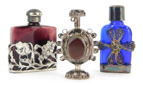 A 20thC blue glass and silver mounted scent bottle, with floral filigree decoration to the body, marked 925, 6.5cm high, together with an eastern white metal and stone set scent bottle, 6cm high, and a ruby glass scent bottle with plated floral decoration