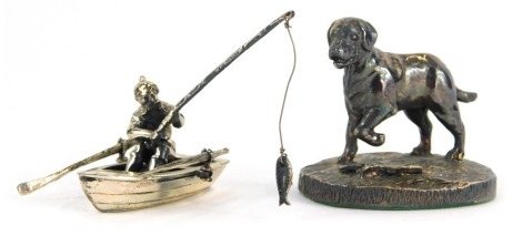 An Elizabeth II silver model of dog with one paw raised, the side branch on naturalistic base, Sheffield 2001, 5cm high, together with a silver model of a fisherman in boat, marked 925, 3cm high. (2)