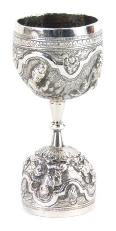 An eastern white metal jigger, repousse decorated with figures in various poses, 10cm high.