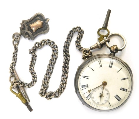 A Victorian silver pocket watch, with white enamel Roman numeric dial, gold hands and seconds dial, with a crested back, key wind, with watch chain with T bar and shield fob, 150.2g all in.